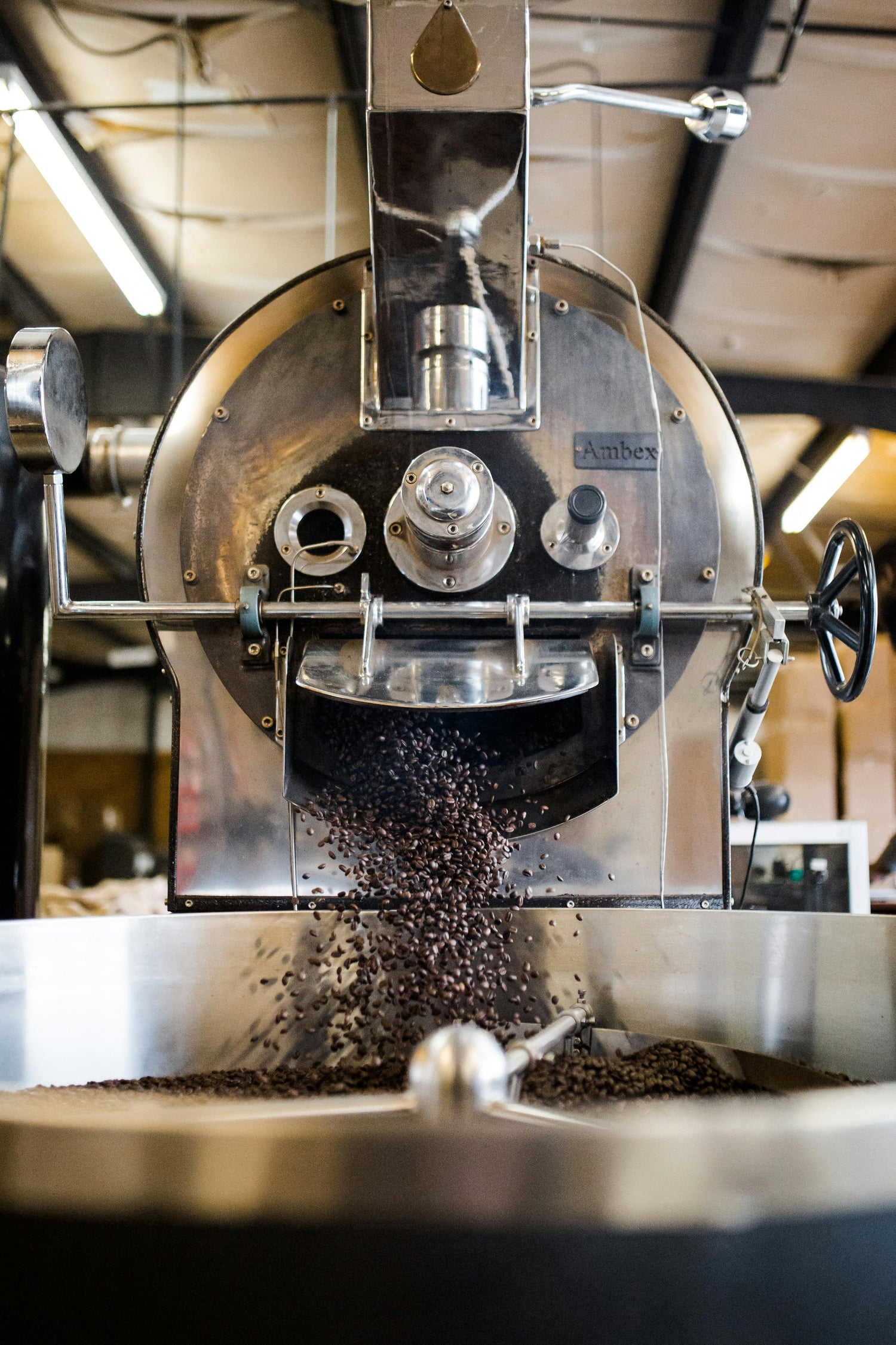 Coffee roasting machine in action with coffee beans being expelled.