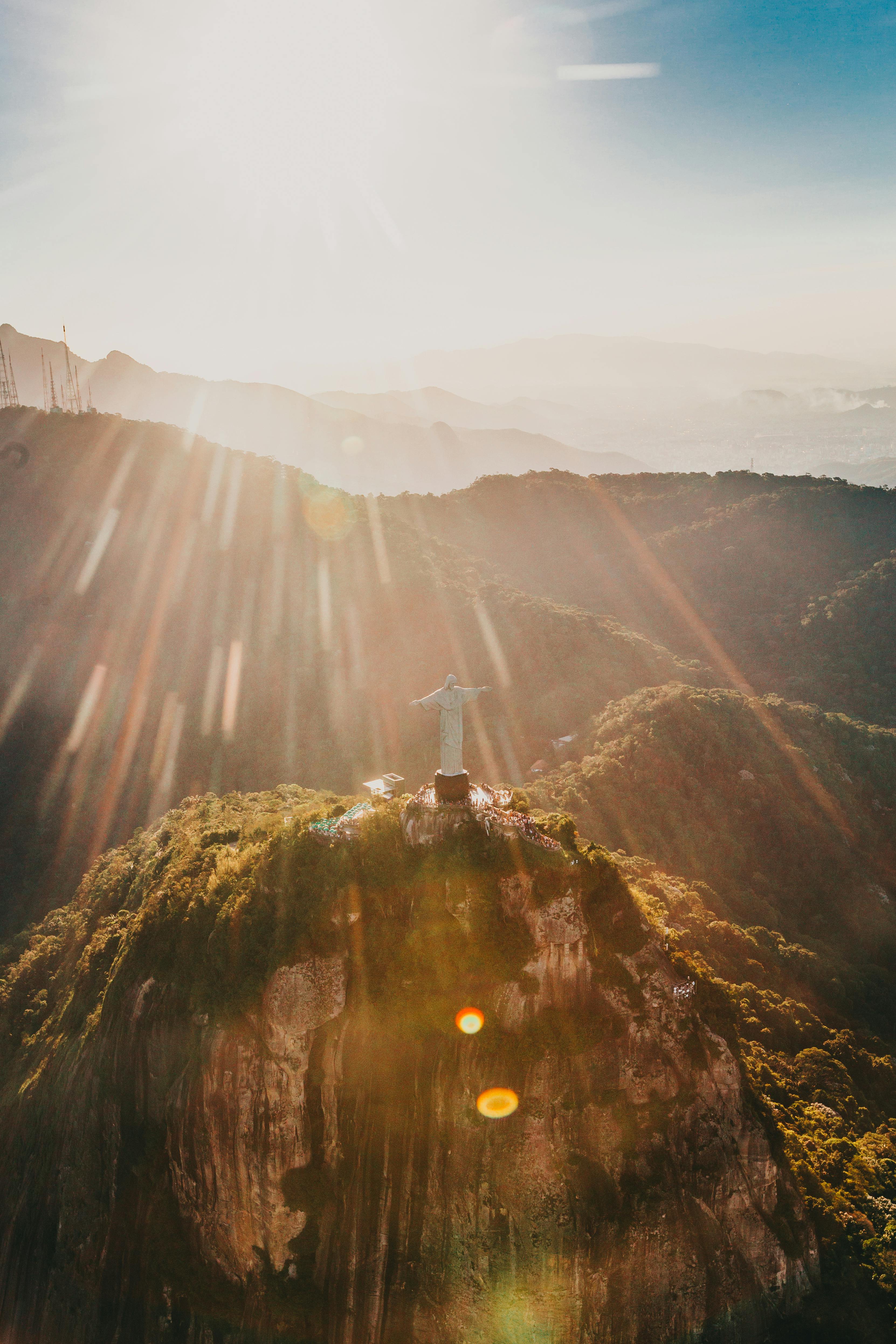 Statue of Christ the Redeemer on a mountain with sun rays shining through