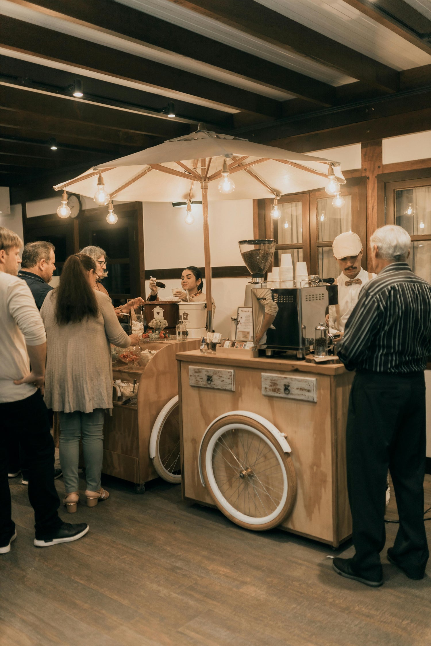 Wooden coffee cart with people around in a cozy indoor setting