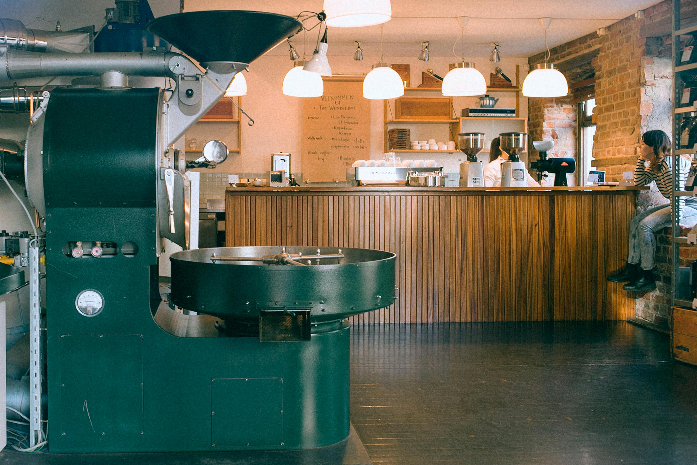 Coffee roasting machine in a coffee shop with a counter and people in the background