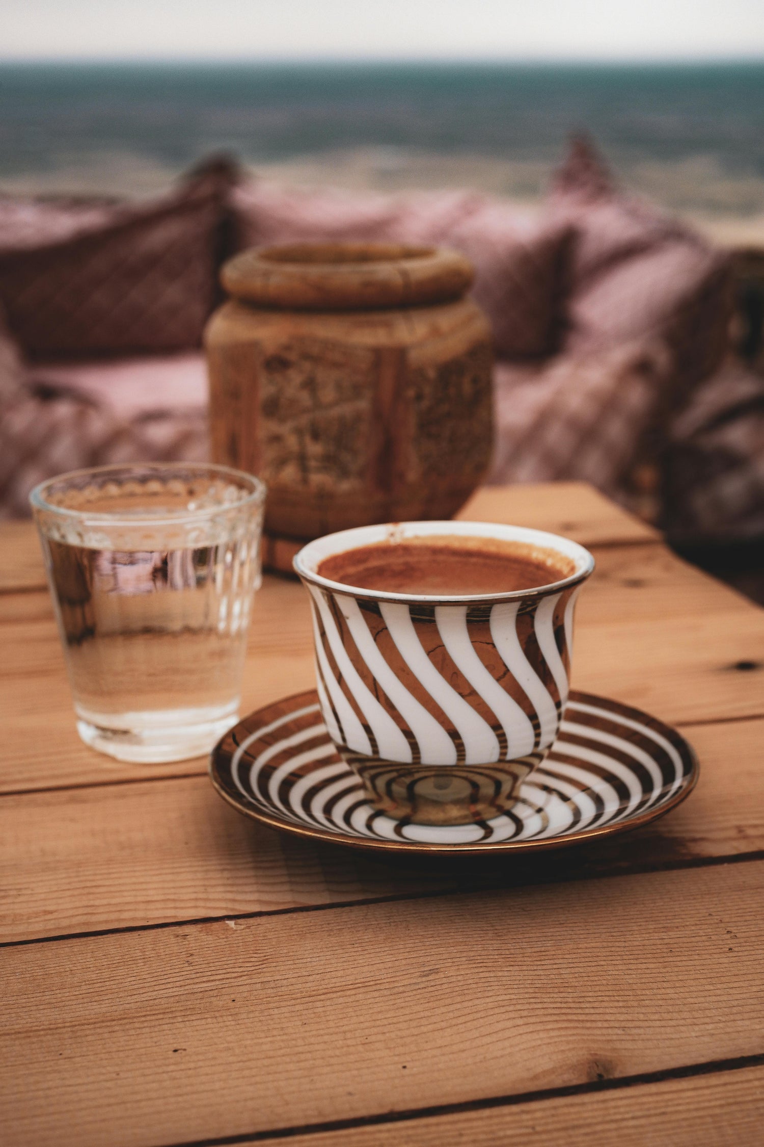 Striped coffee cup and glass on a wooden table with a blurred natural background