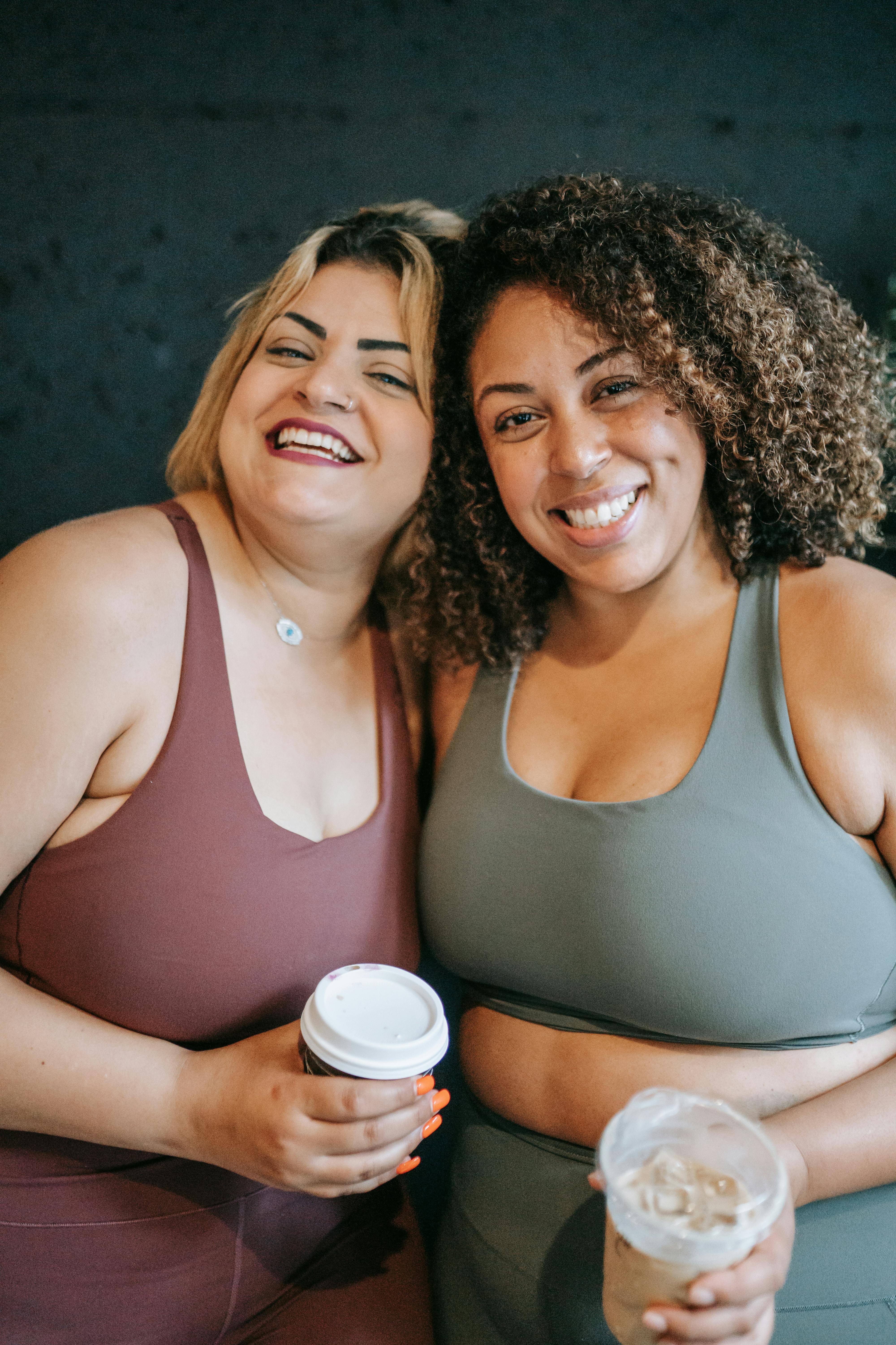 Two women holding coffee cups against a dark background