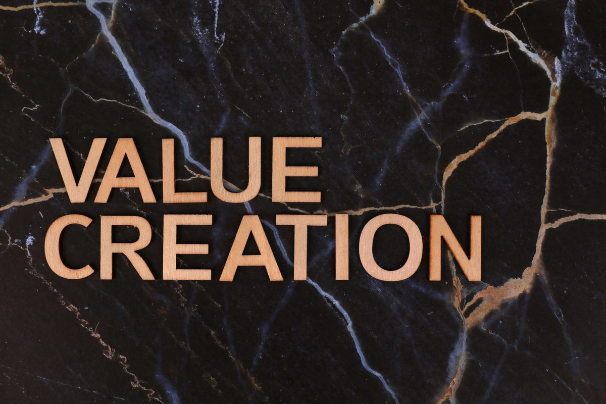 The words 'VALUE CREATION' in a warm peach-pink sans-serif font, overlaid on a dark black marble background with white and gold veining.