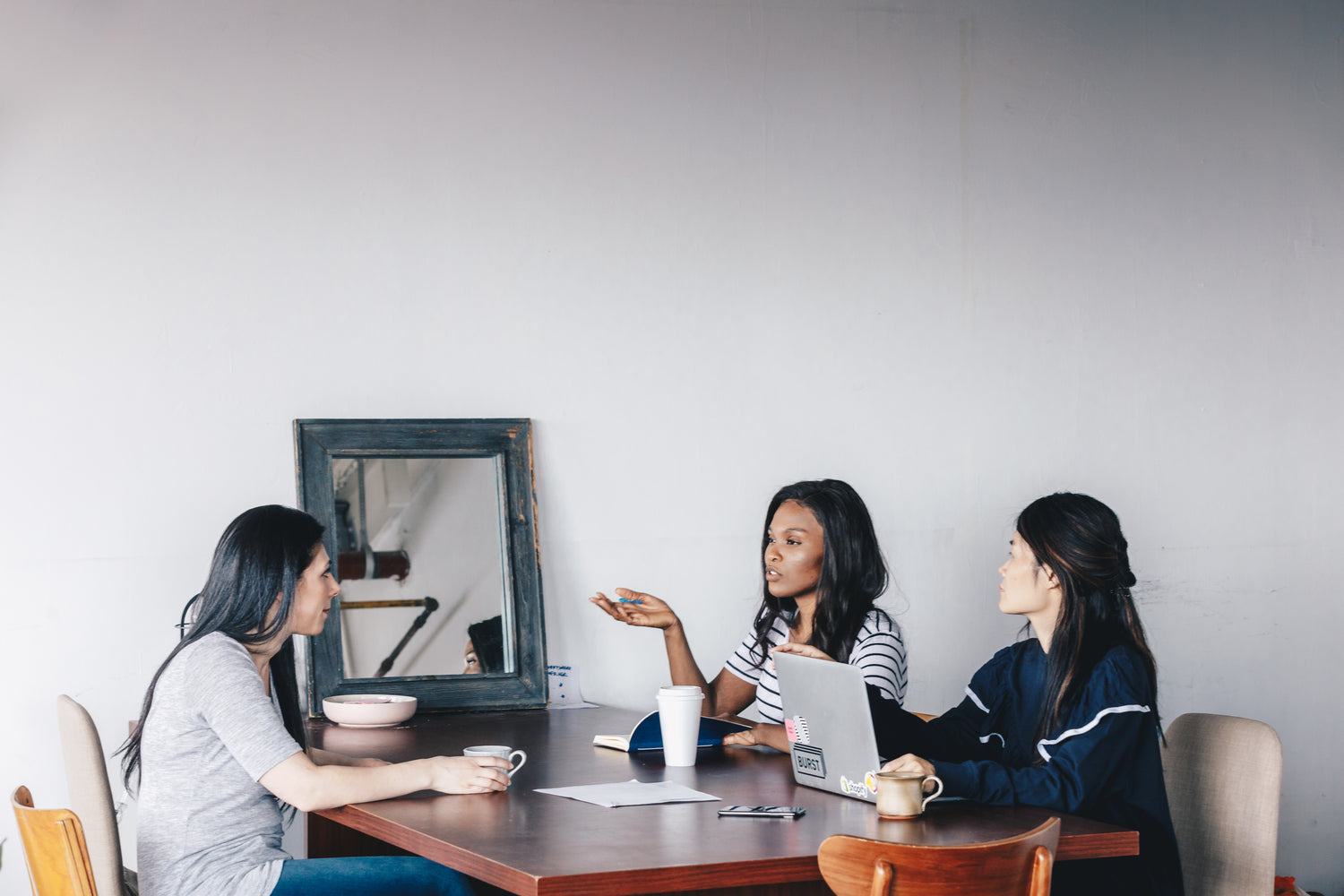 three-woman-hold-a-meeting-at-a-dark-wooden-table